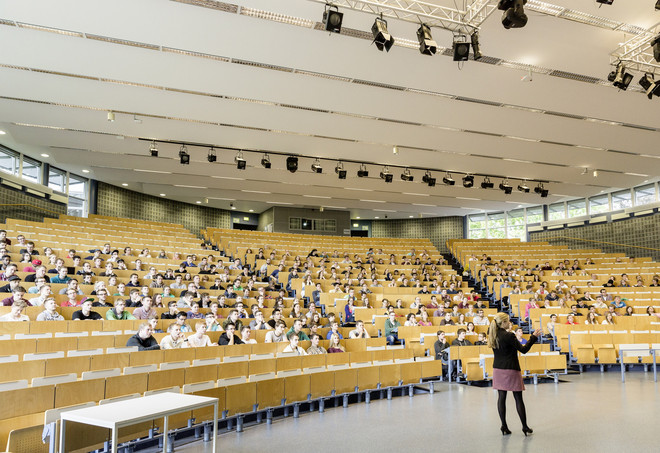 Ein großer Hörsaal mit Studierenden in den Sitzreihen und einer Dozentin vorne.