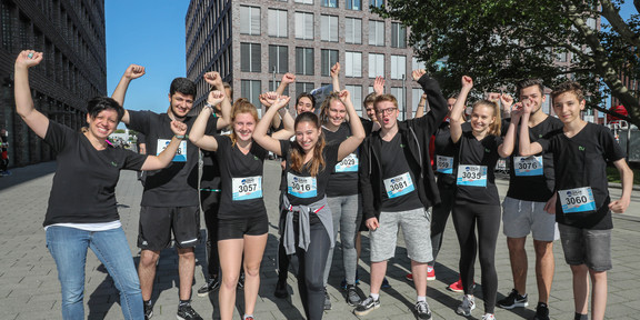 Eine Gruppe schwarz gekleiderter, sportlich aussehender Personen jubelt