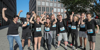 Urban Trail Eine Gruppe schwarz gekleiderter, sportlich aussehender Personen jubelt