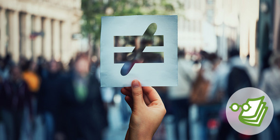 Schild Eine Hand hält in einer Straße mit mehreren Menschen ein Blattpapier hoch mit einem Ungleichzeichen darauf gedruckt.