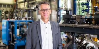 Ein Foto von einem Mann mit Brille in einem Anzug.