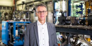 Ein Foto von einem Mann mit Brille in einem Anzug.