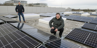 Two men on a roof with photovoltaic panels