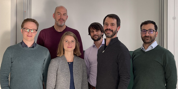 Foto: Eine Gruppe von Personen steht vor einer Präsentationsfolie mit dem Titel „GaiaIsotopic“ an der TU Dortmund, die ein technisches Gerät und Projektinformationen zeigt.