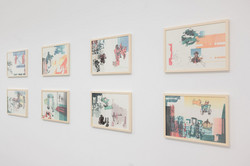 Ausstellung Goldenes Wunder Acht gerahmte Bilder hängen an einer weißen Wand.