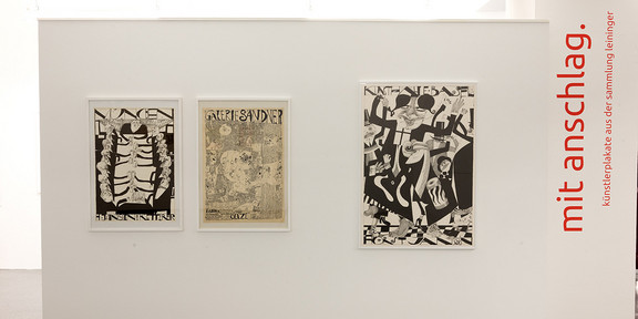 Ausstellung mit anschlag. Drei Plakate der Ausstellung und an der rechten Seite in roter Schrift mit anschlag.