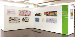 Das Bild zeigt einen Ausstellungsraum mit Bildern.