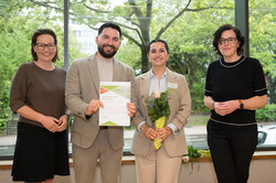 In the photo, four people are smiling at the camera after the certificates were presented.