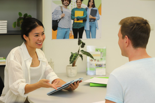 Beratungssituation ZSB 1 Studienberaterin berät Studenten an einem Tisch. Die Studienberaterin hält ein Tablet in der Hand.