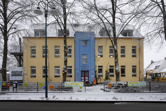 Auf dem Foto sieht man ein gelb-blaues Gebäude (die Aloysiusschule in Holzwickede).