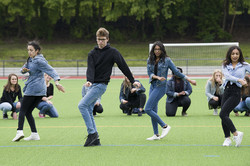 Mehrere Personen tanzen HipHop auf einer Rasenfläche.