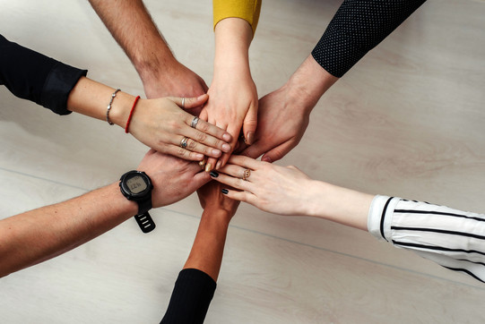 hands of six people laid on each other