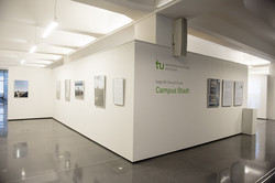 Ein Ausstellungsraum mit Fotografien. An einer Wand steht: "Die TU Dortmund begrüßt Sie auf ihrem Campus Stadt.“