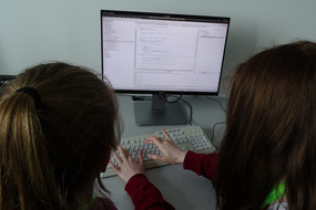 Zwei Teilnehmerinnen entwickeln am PC einen Quellcode.