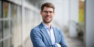 A portrait of a man with short hair, smiling at the camera.