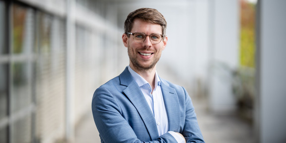 A portrait of a man with short hair, smiling at the camera.