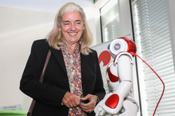 A woman stands next to a robot