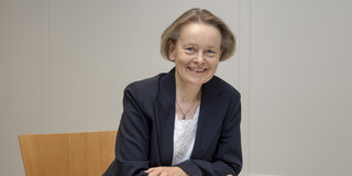 Ein Porträtbild von einer Frau sitzend am Schreibtisch, die Frau ist Prof. Beate Kowalski.