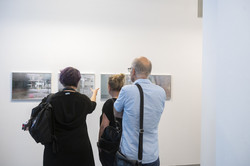 Zwei Frauen und ein Mann stehen vor vier Fotografien, die die Spiegelungen in leeren Schaufenstern zeigen.