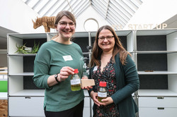 TU Sieger Junge Spitzenforschung - Siegerfoto Platz 4 Auf dem Foto in Normalperspektive sind die zwei Viertplatzierten mit einer Glasflasche mit der Aufrschrift Öl-Krieger und ihrem Preis zu sehen.