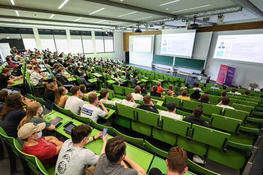Westenergie Manager Cup Auftaktveranstaltung Mehrere Studierende sitzen in einem Hörsaal mit grüner Bestuhlung.