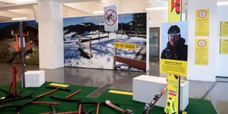 Ausstellung über den Wintersport in den Bergen, mit Bildern von verschneiten Landschaften und Skiausrüstung im Vordergrund. 