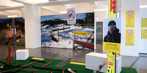 Exhibition about winter sports in the mountains, with pictures of snow-covered landscapes and ski equipment in the foreground. 
