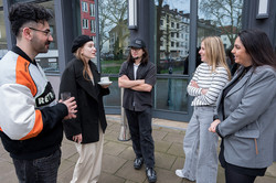 A group of people talks outside in front of a building.