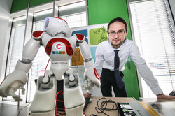 Man bending over a table to a robot