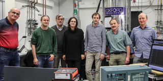 Several men and a woman stand in a row in a laboratory.