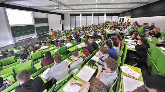 Studierende bei einer Vorlesung im grün bestuhlten Hörsaal