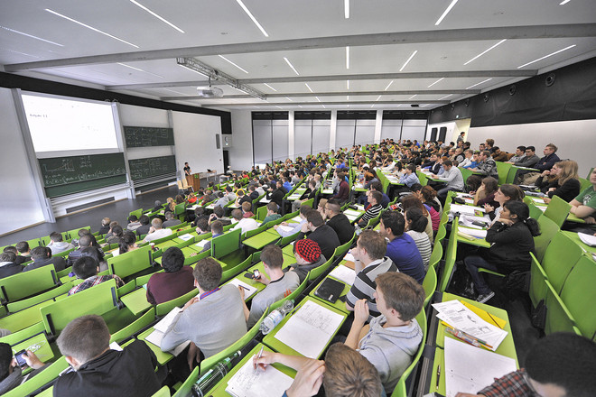 Studierende bei einer Vorlesung im grün bestuhlten Hörsaal