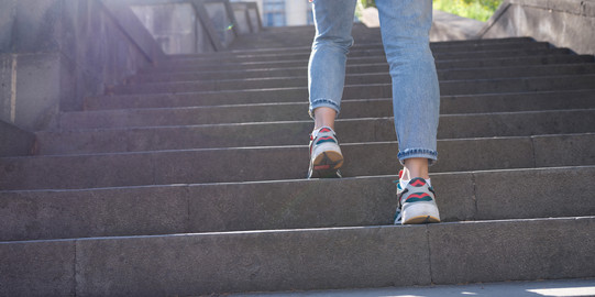 Eine Person trägt eine Jeanshose und Sneaker und läuft Treppen hoch. 