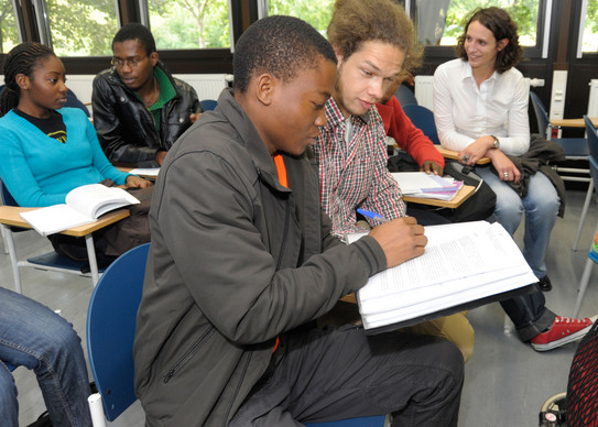 Internationale Studierende Studentinnen und Studenten unterschiedlicher Hautfarben sitzen in einem Seminarraum und sprechen miteinander