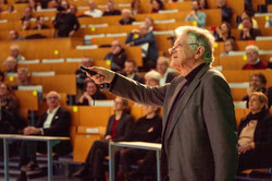 Prof. Dr. Klaus von Klitzing zeigt mit einem Laserpointer auf etwas. Im Hintergrund die Ränge eines Hörsaals.