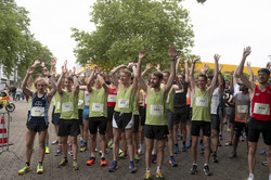 Campuslauf-Teilnehmende reißen an der Startlinie ihre Arme hoch.