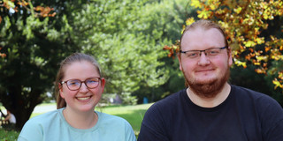Foto: Annika Ricke und Darius Weitekamp stehen auf dem Campus der TU Dortmund. Im Hintergrund sieht man Bäume.