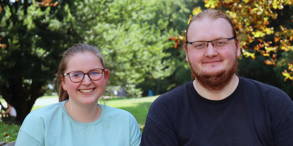 Foto: Annika Ricke und Darius Weitekamp stehen auf dem Campus der TU Dortmund. Im Hintergrund sieht man Bäume.