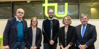 Fünf Personen in dunklen Sakkos und Blazern vor einem TU-Logo.