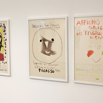 Drei Künstlerplakate von Ausstellungen über Miro und Picasso hängen nebeneinander an einer weißen Wand. 