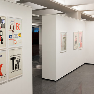 Mehrere Künstlerplakate von Josua Reichert hängen an einer weißen Wand.