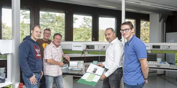 Netzwerk Elektroniker Fünf Männer stehen in einer Werkstatt.