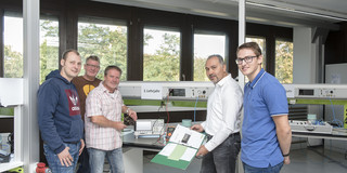 Netzwerk Elektroniker Fünf Männer stehen in einer Werkstatt.