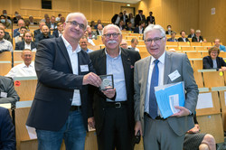 TU-Rektor Prof. Manfred Bayer steht mit Prof. i.R. Matthias Kleiner und Prof. A. Erman Tekkaya in einem Hörsaal.