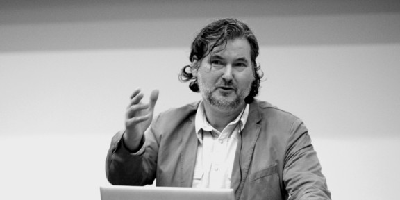 Foto in schwarz-weiß: Prof. Bastiaens steht an einem Redepult und gestikuliert.
