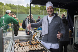 Eine Person grillt Würstchen an einem großen Grill.