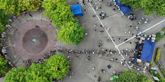 Photo: A shot of the TU Dortmund campus from above. The photo shows many people walking across the campus.