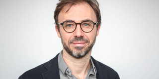 Portrait of Dortmund phyiscist Prof. Dr. Mirko Cinchetti: a middle-aged man with brown hair, beard and glasses smiles slightly into the camera