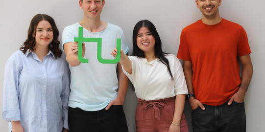 Gruppenfoto von Studierenden studierende halten das TU Logo hoch
