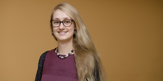 Portrait von Vanessa Mertens vor einer orangenen Wand